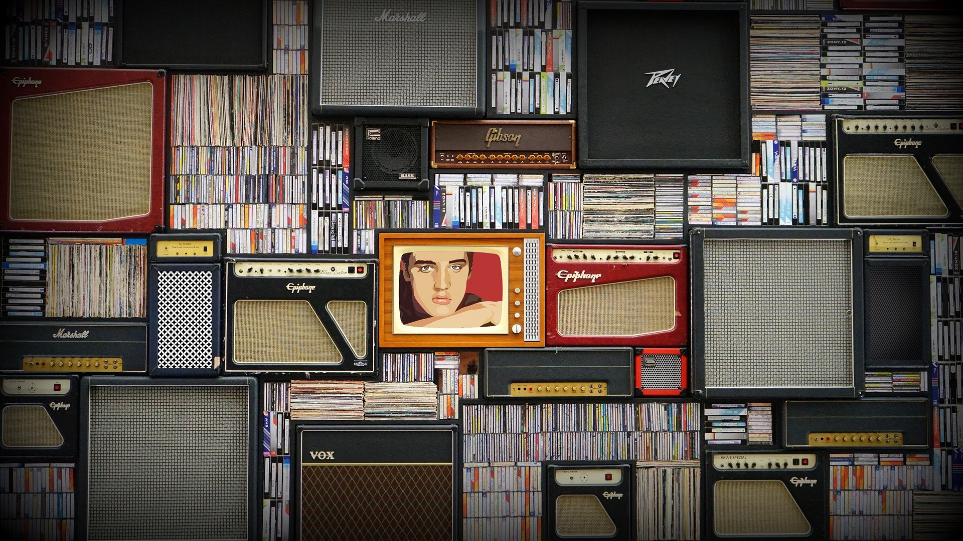 A wall display featuring vintage radios and speakers against a wallpapered backdrop.