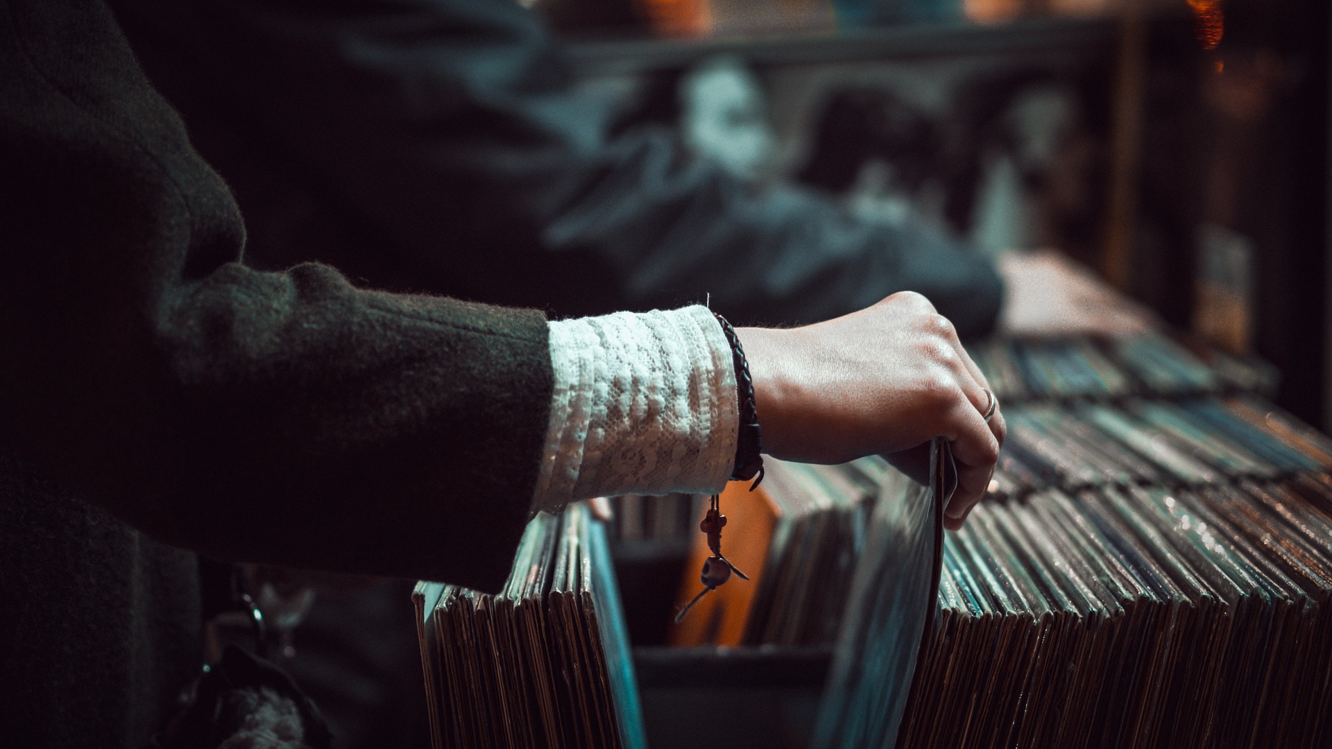 A person browsing vinyl records, selecting one with their hand.